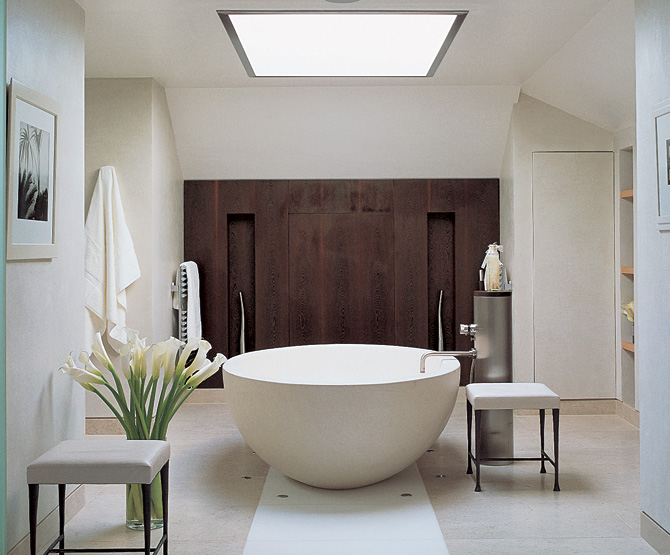 The beautiful stone bath is a focal point in this wonderful bathroom designed by Kelly Hoppen. The effect is enhanced by dark wall behind it which immediately draws attention of a person coming inside. 